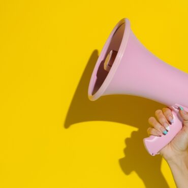 A,Woman’s,Hand,Holding,A,Pink,Megaphone,Isolated,On,A